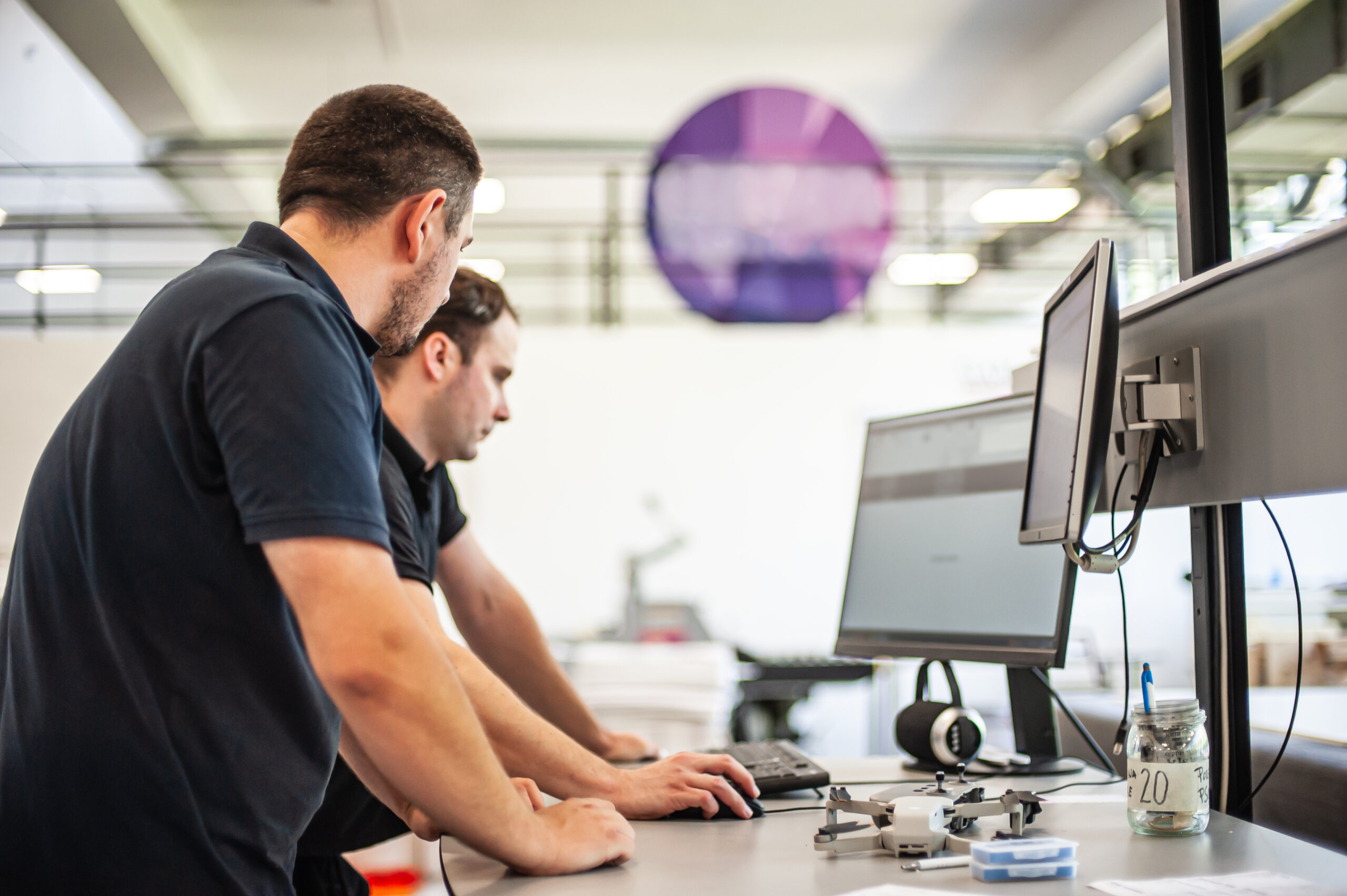 Two men stood next to computer screens