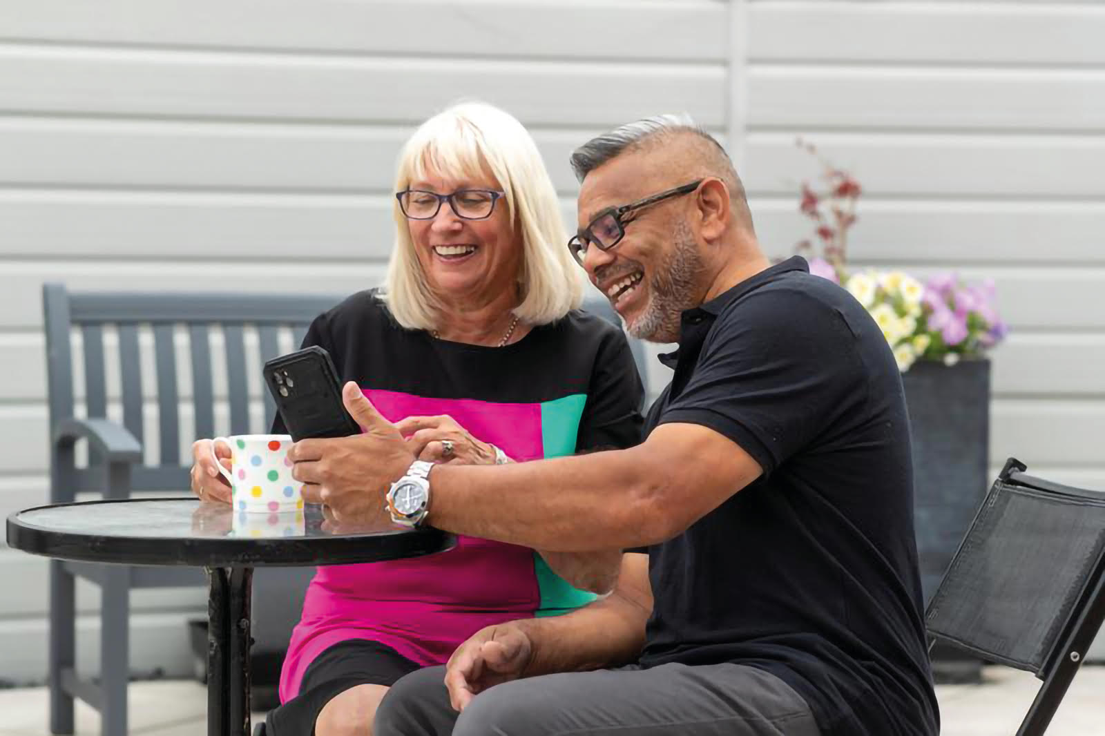 Couple at pension age smiling as the look at their phone