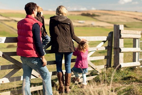 Family stood by a farmland field gate